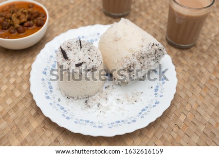 White Puttu, Pittu, Kadala curry, hot and spicy chickpea Masala and milk tea Kerala breakfast India on palm mat background, Top view South Indian veg food. steamed made of rice flour, grated coconut  