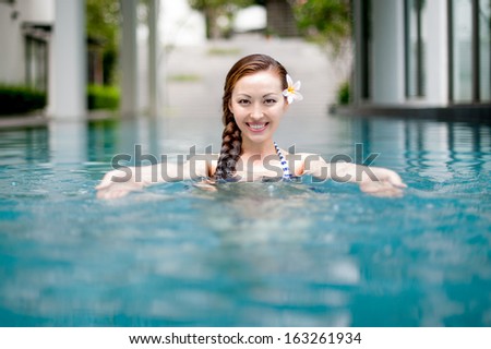 Attractive Asian Woman in Pool welcoming with a smile 