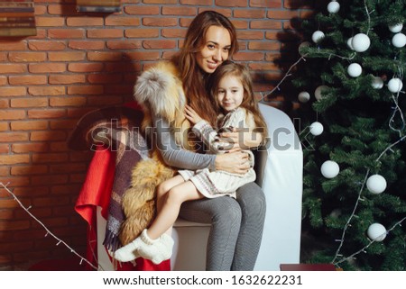 Cute mother with little daughter. Family sitting near Christmas tree.