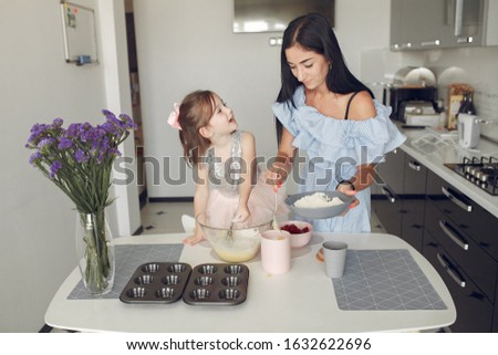 Family in a kitchen. Mother with little daughter. Flour at the table.