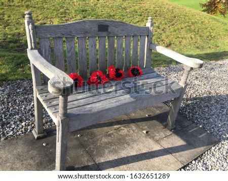 Picture of a bench with poppies on it at the memorial arboretum
