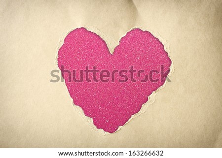 pink heart shape made from torn paper over glitter boke soft lights.
