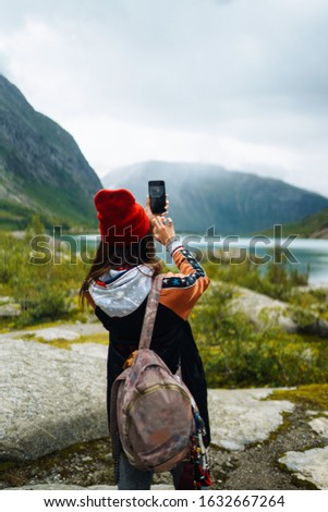 Stylish woman takes a photo on the phone in the travelling. The girl tourist photographs a picturesque landscapes.Travelling, lifestyle, adventure, concept.