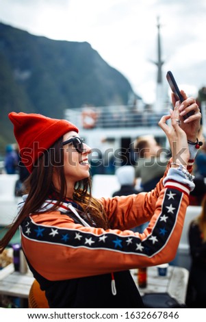 Stylish woman takes a photo on the phone in the travelling. The girl tourist photographs a picturesque landscapes and views. Travelling, lifestyle, adventure, concept.