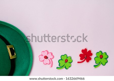 March 17 is the feast of St. Patrick. Green felt hat and shiny paper clover leaves on a white background.

