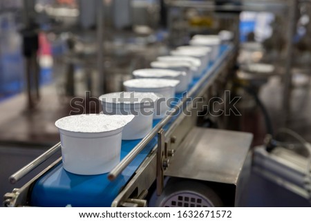 White yogurt packages on a production line in a dairy farm. Royalty-Free Stock Photo #1632671572