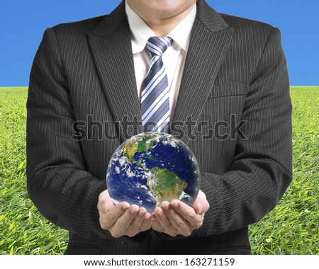 Businessman two hands hold ball with global map with fresh green meadow and clear blue sky, Elements of this image furnished by NASA