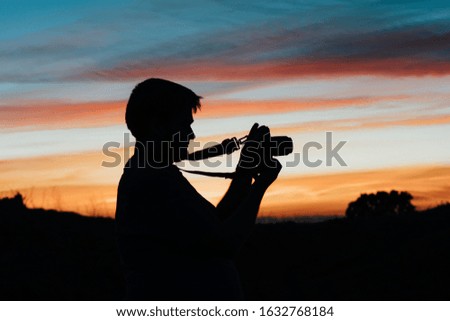 A man taking pictures with his analog camera in a sunset at golden hour