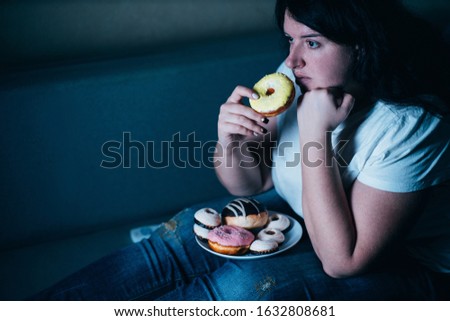 Sugar addiction, unhealthy lifestyle, weight gain, dietary, healthcare and medical concept. Cropped portrait of overweight depressed woman laying on sofa eating sugary food watching TV Royalty-Free Stock Photo #1632808681