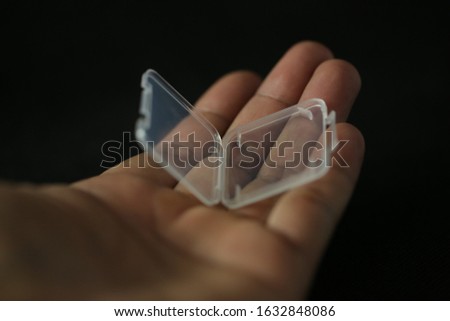The Sd card transparent cover on the palm with black background.