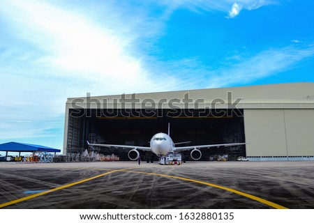 Aircraft towing tractors towing aircraft (airplane) out from aircraft hangar after finished maintenance. Royalty-Free Stock Photo #1632880135