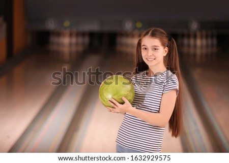 Preteen girl with ball in bowling club. Space for text