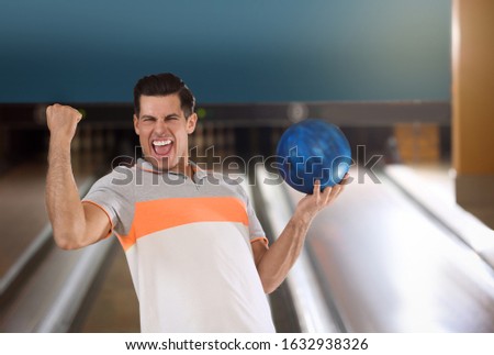 Excited man with ball in bowling club