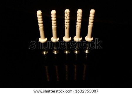 Four wall dowel pin with screw isolated on black with reflections