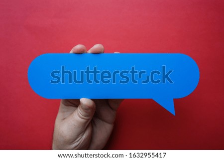 Man holding blank blue speech bubble on red background.