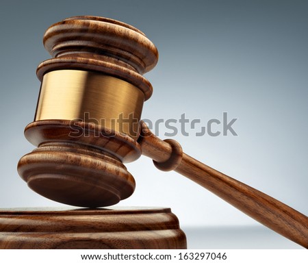 A wooden judge gavel and soundboard on blue background in perspective