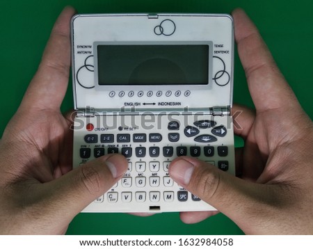 Electronic dictionary with the concept of the position of a finger touching the button and a green background.