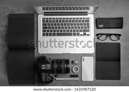 Flat lay composition with laptop, camera and smartphone on grey stone table. Designer's workplace