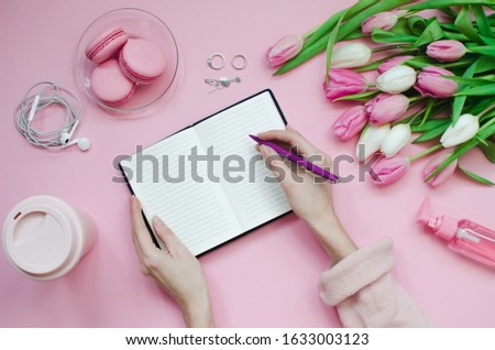 Girl writing wish list for future plans. flat lay composition with flowers, notepad, a cup of coffee and sweets