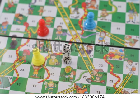 Snakes and Ladders Board Game, Snakes, ladders, start, finish
 with selective focus and blured, isolated white blue background. 
