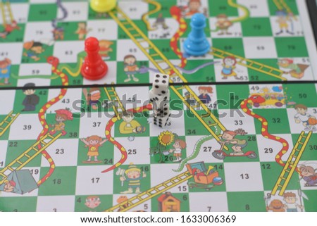 Snakes and Ladders Board Game, Snakes, ladders, start, finish
 with selective focus and blured, isolated white blue background. 
