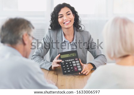 Financial Advice. Professional insurance agent holding calculator, showing amount of insurance case to elderly couple
