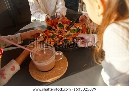 Top view image of children hands grab slice pizza. Group of kids eating italian food in in cafe. Hungry children holding appetite piece of tasty pizza. People celebrating birthday in pizzeria.