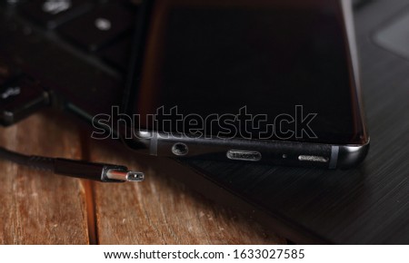 picture of a USB type C cable, which is connected to a laptop and which is ment to be plugged in a modern phone