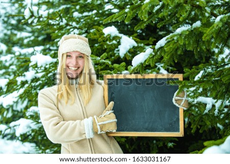 Happy girl. Place for ad. A young girl holds a board. Winter discounts concept.