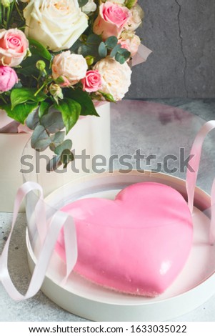 Gift set - pink heart-shaped mousse cake and a large bouquet of beautiful flowers on the grey grunge background. Valentine's Day. Mothers Day card