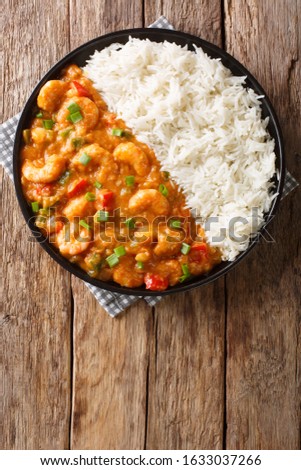 Louisiana shrimp Etouffee with vegetables cooked in roux sauce served with rice closeup in a plate on the table. Vertical top view from above
