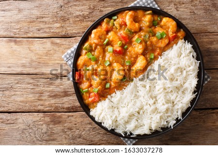Serving of shrimp Etouffee with vegetables and sauce served with rice closeup in a plate on the table. Horizontal top view from above
