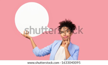 Maybe. Pensive afro woman holding blank speech bubble, touching her chin, looking up, copyspace, pink studio wall
