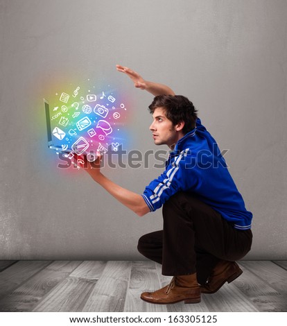 Casual young man holding laptop with colorful hand drawn multimedia symbols