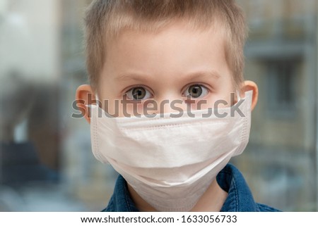 Toddler boy with a medical mask on his face/ Warning of the dangers of traveling to China and safety measures against coronavirus/2019 nKoV Coronavirus originating in Wuhan, China/  Close-up portrait Royalty-Free Stock Photo #1633056733