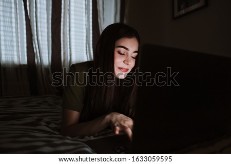 Smiling young european woman lying on sofa at home, working distantly on computer. chatting with friends in social networks, studying online, surfing information.