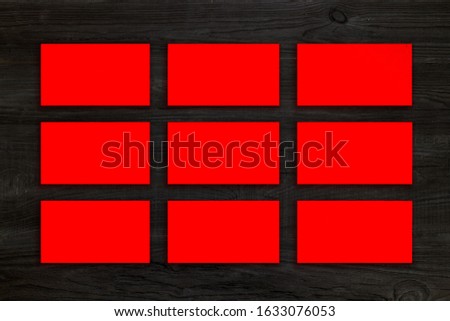 Mockup of horizontal red business cards stacks arranged in rows at black wooden background