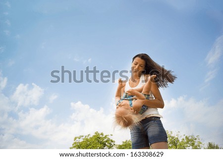 Happy young mother having fun with her son in nature
