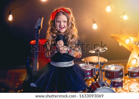 little beautiful girl with curly hair singing in recording studio.