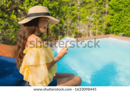 Portrait young asian woman read book around outdoor swimming pool in hotel resort