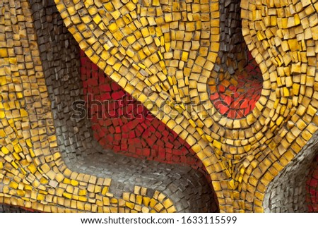 Texture of a wall made of small stones. The wall is clad with yellow, red and white granite cubes.