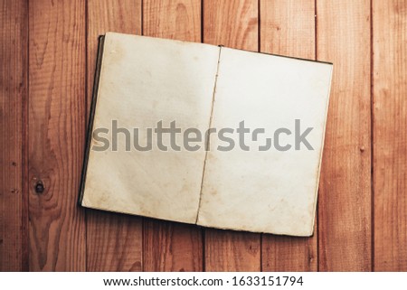 Open Vintage book on a red wooden table background. Top view.
