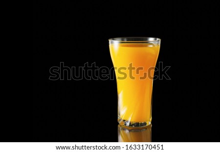 Orange juice glass on a black background