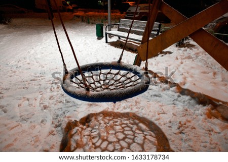 Seesaw in a yard of a living block. Russia, night winter view.