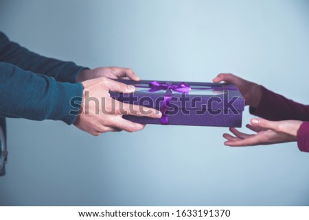 man and woman hand gift box on grey background