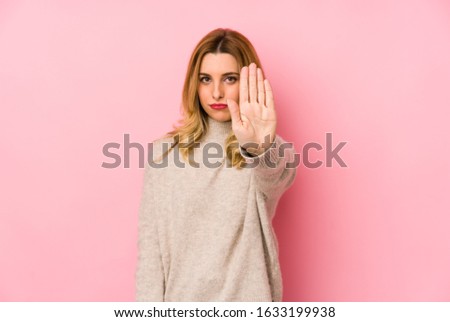 Young blonde cute woman wearing a sweater isolated standing with outstretched hand showing stop sign, preventing you.