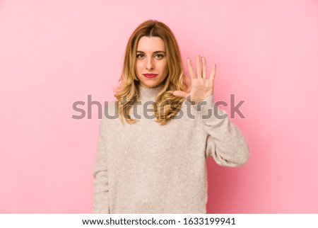 Young blonde cute woman wearing a sweater isolated smiling cheerful showing number five with fingers.