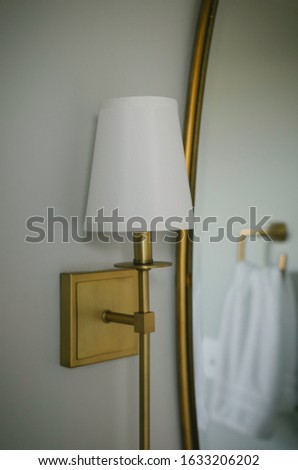 Golden light sconce next to mirror
