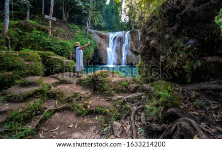 Beautiful woman and green waterfall in the nature, Than Sawan Waterfall in Payao province, Thailand. 