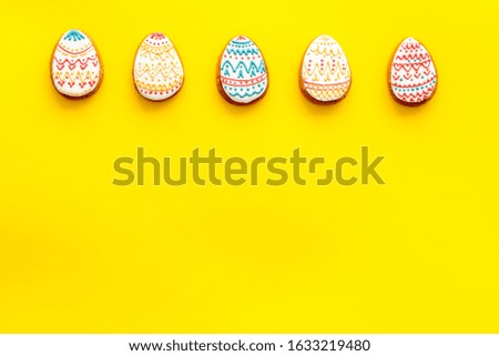 Sweets for celebrate Easter. 
Gingerbread in shape of easter bunny,easter eggs and carrot . Yellow background top view mockup